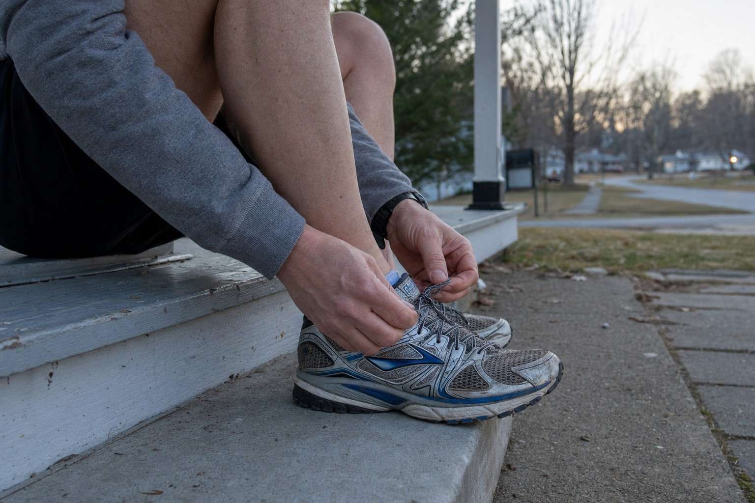 Close view of a runner lacing up shoes on a porch step