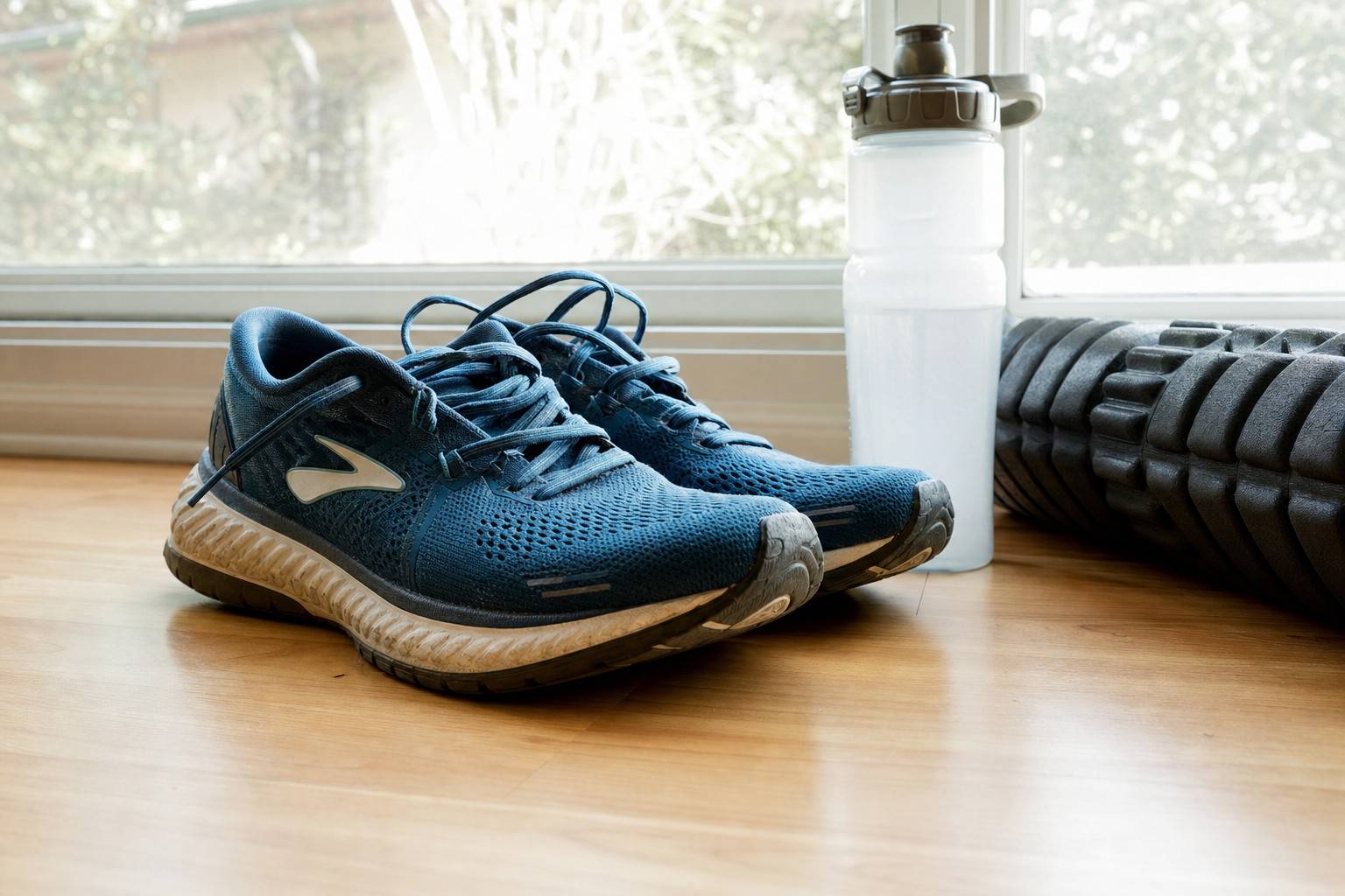 Running shoes at rest by a window with a foam roller