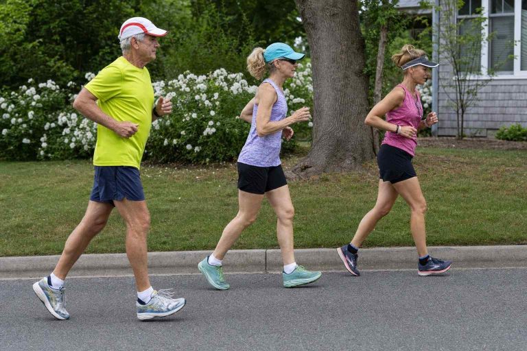A small group of runners jogging on a neighborhood street