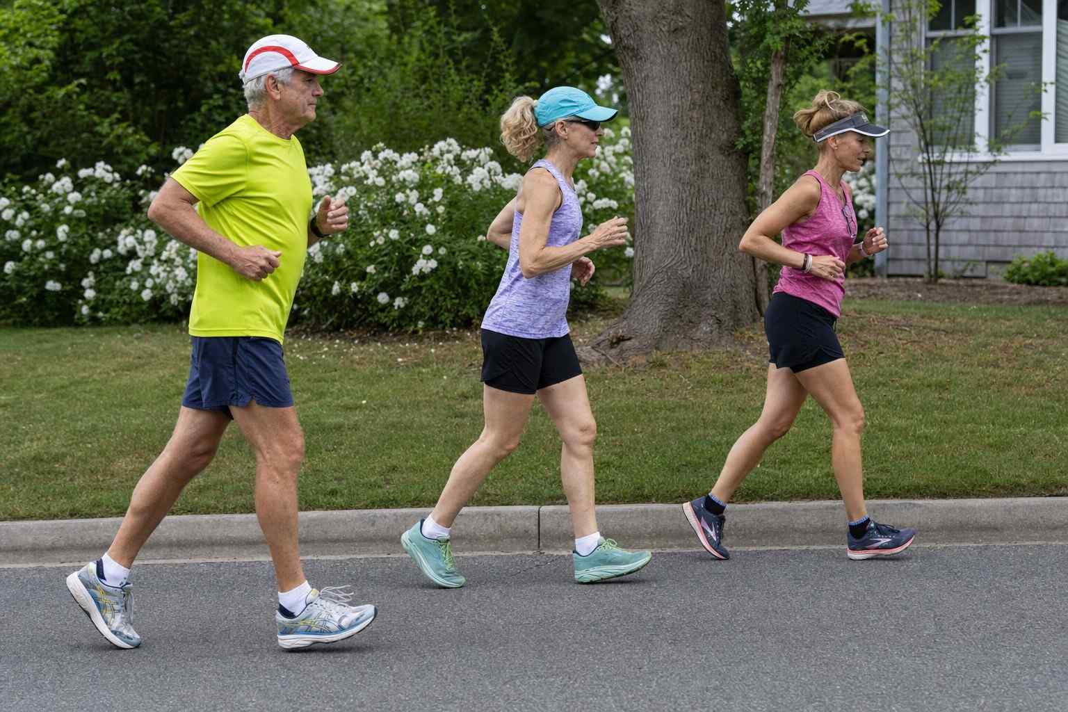 A small group of runners jogging on a neighborhood street